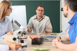 © Pixel-Shot - Male teacher talking to his colleagues at table in school office