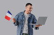 © Pixel-Shot - Young man with flag of France and laptop on grey background
