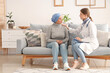 © Pixel-Shot - Mature woman after chemotherapy with doctor at home. Stomach cancer concept