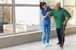 © Pixel-Shot - Nurse helping senior man with stick to walk at hospital