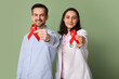 © Pixel-Shot - Handsome adult man and female doctor with red ribbons on green background. World AIDS Day concept