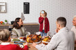 © Pixel-Shot - Happy family playing word guessing game at festive table on Thanksgiving Day