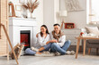 © Pixel-Shot - Young couple holding hands near fireplace at home
