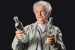 © Pixel-Shot - Displeased senior woman with bottles of vodka on black background