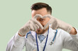 © Pixel-Shot - Male doctor making heart with his hands on green background, closeup