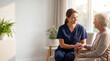 © Polani - An adult female nurse sitting beside an adult senior female patient in a bright, peaceful care room