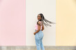 © VISTA by Westend61 - Casual woman smiles and turns by a pastel wall outdoors