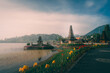© Travel 'n' Lifestyle - View of the iconic Ulun Danu Beratan Temple on the shores of Lake Beratan with vibrant yellow flowers in the foreground and mountains in Baturiti, Bali, Indonesia.