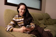 © Elena Kharichkina/Stocksy - Woman uses smartphone while relaxing on couch