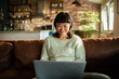© Davor - Woman using laptop on sofa at home