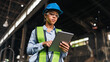 © chokniti - Engineer worker safety helmet tablet factory woman vest inspection focused female engineer using tablet in industrial factory, wearing safety gear during work