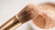 © TransPicHub - A close-up of a makeup brush applying shimmering rose gold eyeshadow powder with a soft blurred background.