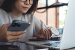 © tippapatt - Focused woman working on laptop, browsing the internet and using smartphone at modern office, close up. Remote work,  online business lifestyle concept.