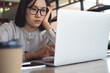 © tippapatt - Close up of a burned-out asian woman sitting at cafe, staring at her laptop with low energy, low motivation burnout cobcept