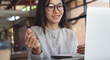 © tippapatt - Smiling young asian businesswoman making finger heart gesture on video call, working on laptop in cafe workspace.