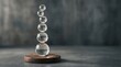 © Yoshi - Transparent glass spheres stacked in a delicate vertical balance on a wooden base