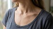 © satya - Close up of womans shoulder and neck wearing a grey t shirt