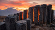 © PLOYCRAMER - Ancient basalt columns illuminated against a stunning sunset backdrop in a mountainous landscape