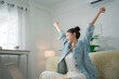 © Thitiporn - Work break and relaxation concept with a young woman stretching her arms beside a laptop at home, enjoying rest after work, relaxation, stretching, wellness, break, lifestyle