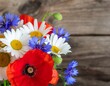 © Suwardiman - Colorful floral arrangement in red vase on rustic table.