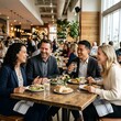 © AamirSohail - Four friends laughing and enjoying a meal together at a busy restaurant