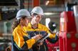 © BESTIMAGE - Engineers team inspecting metal sheet machine system inspection check collaboration in factory Male engineer and female colleague hold clipboard checking machinery at manufacturing plant