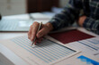 © Tj - Hand of an expert analyzing financial data on a printed report, preparing annual balance sheets and making important investment decisions for future business growth