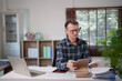 © Tj - Man calculating finances in home office, managing tax documentation, analyzing debt, accounting for personal financial planning and budgeting