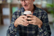© Tj - Man in plaid shirt holding ribbed paper coffee cup with lid, taking a coffee break, enjoying hot drink, having leisure time, warming hands with warm beverage indoor