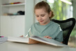 © Volodymyr - Kid reading a book in the living room. Child at home reading a book. Child 10 years old read book fairy tale. Child reading for home learning, story and language education. English books for kids.