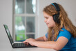 © Volodymyr - Student learns online from home workspace. Student headset supports video classroom meeting. Young girl becomes student during lesson. Homeschool education keeps student focused.
