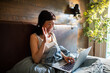 © Davor - Smiling woman video chatting from bed at home