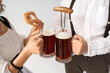 © Pixel-Shot - Mature waiters in traditional German clothes with mugs of beer, sausage and pretzel on grey background, closeup