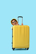 © Pixel-Shot - Happy African-American boy hiding behind suitcase on blue background