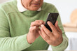 © Pixel-Shot - Senior man using mobile phone in kitchen, closeup