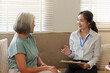 © Natee Meepian - Asian female nurse consulting senior woman during home healthcare visit