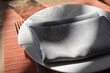 © photoranger2521 - Close-up of modern table setting with grey fabric napkin on a white plate and placemat background.