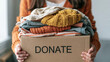© lolipop - Person holding a cardboard box filled with donated clothing for charity non profit donation clothing volunteer kindness community secondhand humanitarian