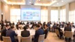 © CuteBee - Blurred business professionals sitting at round tables in large hotel banquet room during corporate event with screens displaying charts and data for seminar or conference gathering