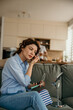 © La Famiglia - Woman applying makeup on sofa in living room