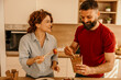© La Famiglia - Couple eating takeaway food with chopsticks in kitchen