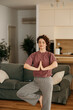 © La Famiglia - Woman practicing yoga tree pose for balance and wellness at home