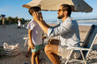 © kleberpicui - A father gently puts sunglasses on his young son beneath a beach umbrella, sharing a warm moment of parental care and sun protection during a relaxed summer family vacation by the ocean.