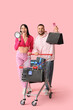 © Pixel-Shot - Young couple with shopping cart and bags shouting into megaphone on pink background. Cyber Monday