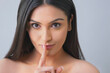 © IndiaPix - Portrait of a pretty young woman gesturing finger on lips over colored background