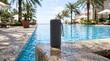 © Firman - Portable speaker enhances vibrant poolside resort ambiance with tropical palm trees and clear blue