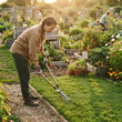 © Duskcraft - Woman using a hand tool to edge grass near flower filled raised garden beds