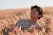 © Andrii Zastrozhnov - Young man relaxing in pink wildflower field background for summer banner and nature lifestyle design