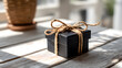© Feefe  - Black gift box tied with brown twine on white wooden table with natural sunlight