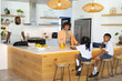 © Wavebreak Media - African American family with two youths in uniform preparing breakfast at kitchen island, backpacks